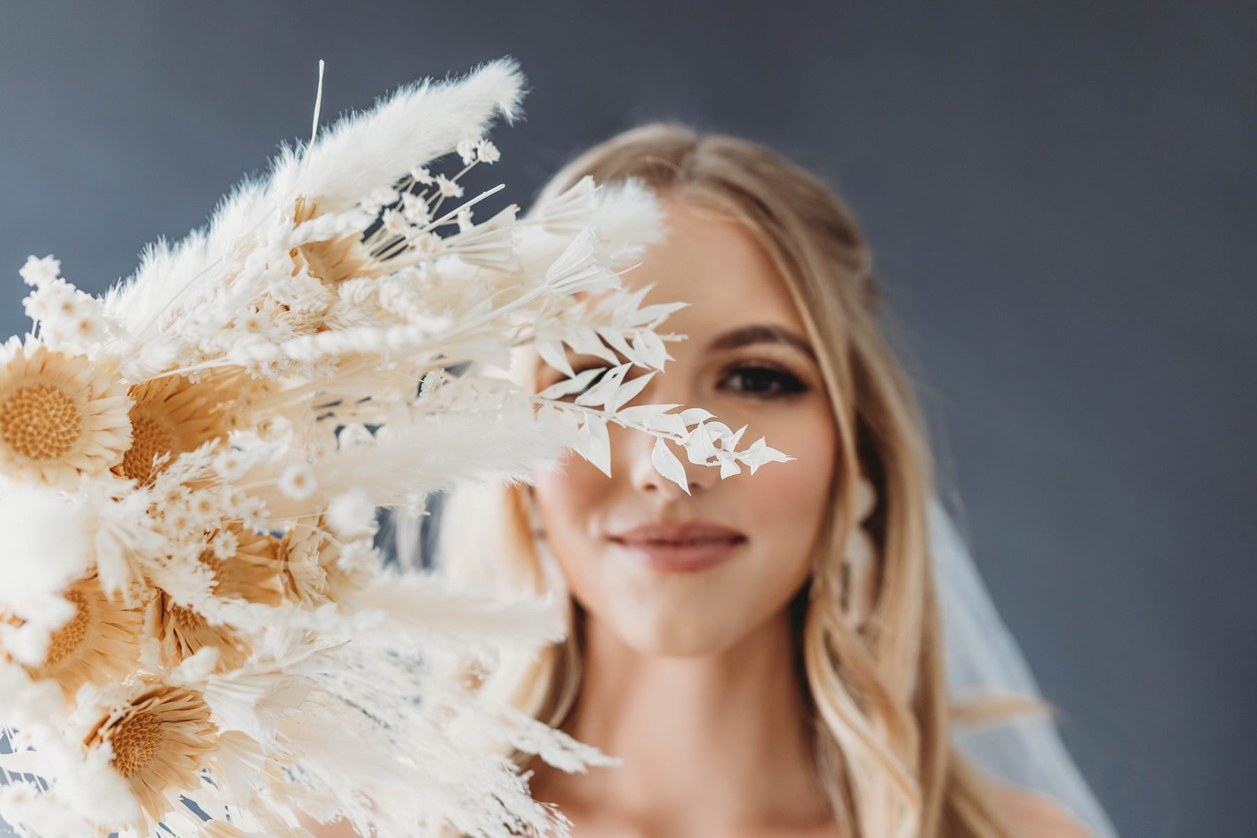 Wedding & Elopement Photographer, bride stands behind floral arrangement, she is happy