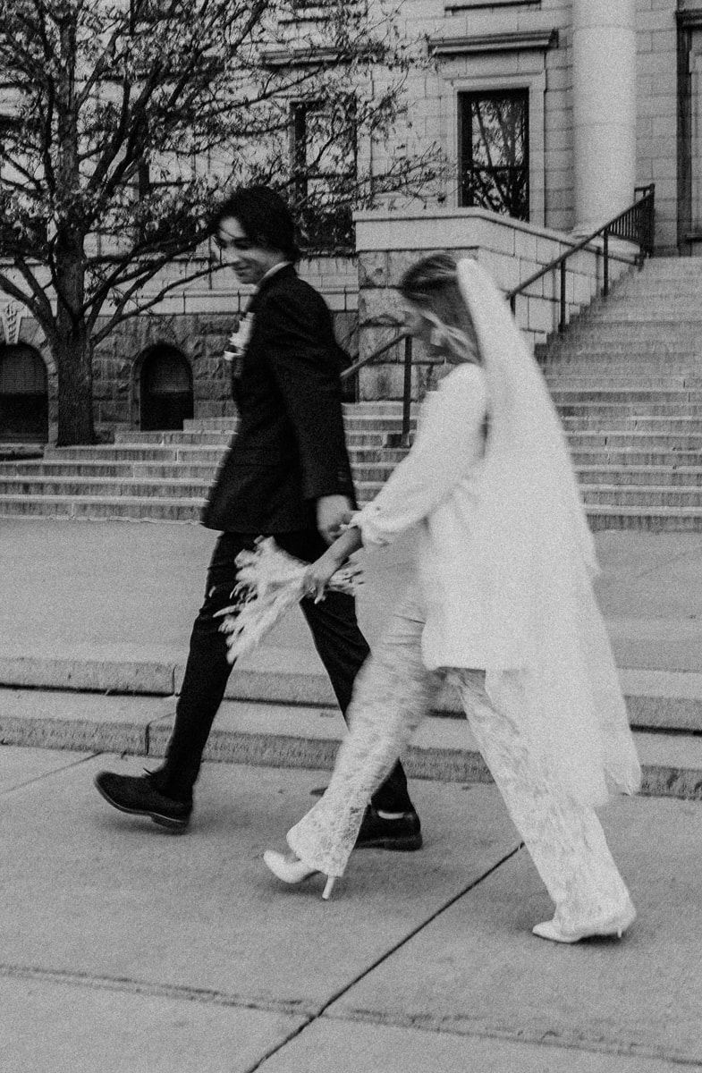 Wedding & Elopement Photographer, bride and groom hold hands as they walk down city sidewalk
