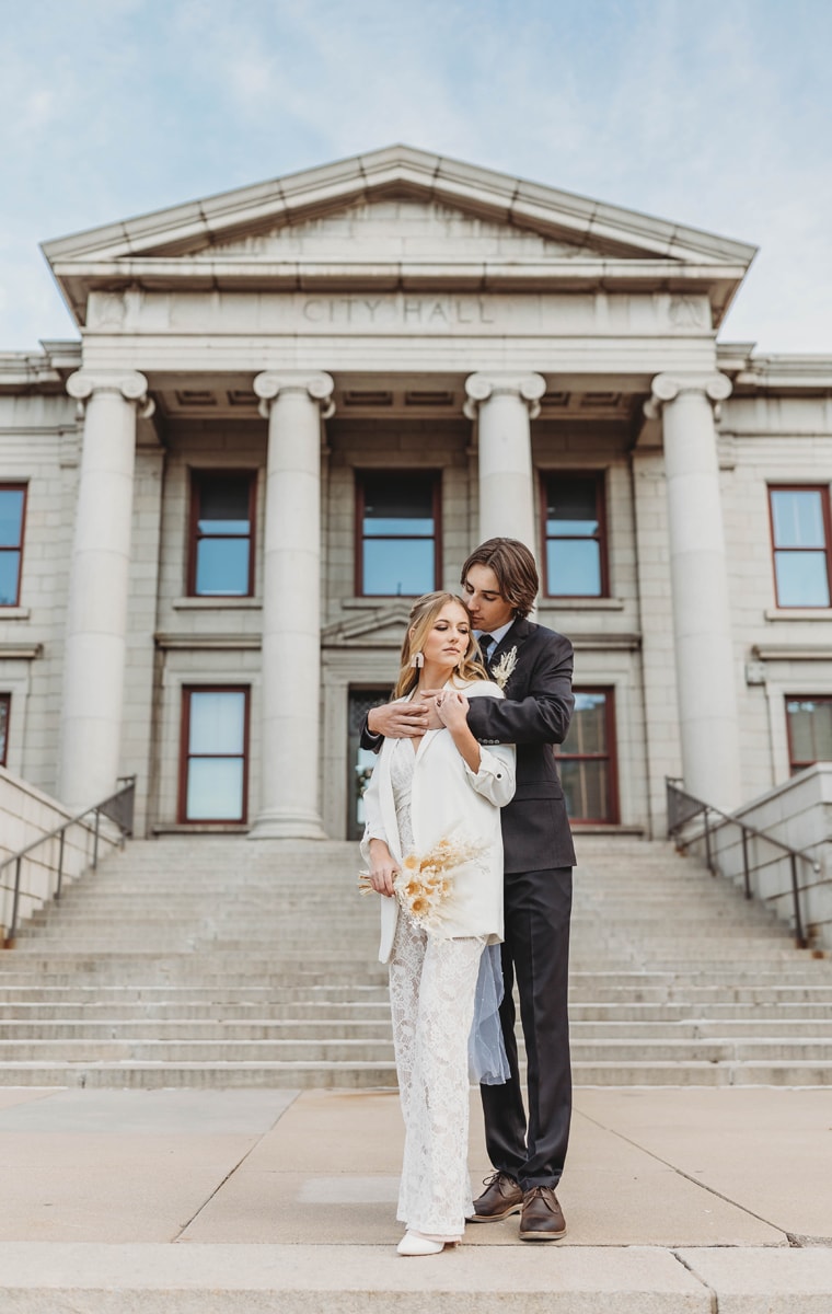 Wedding & Elopement Photographer, a bride and groom embrace standing before City Hall