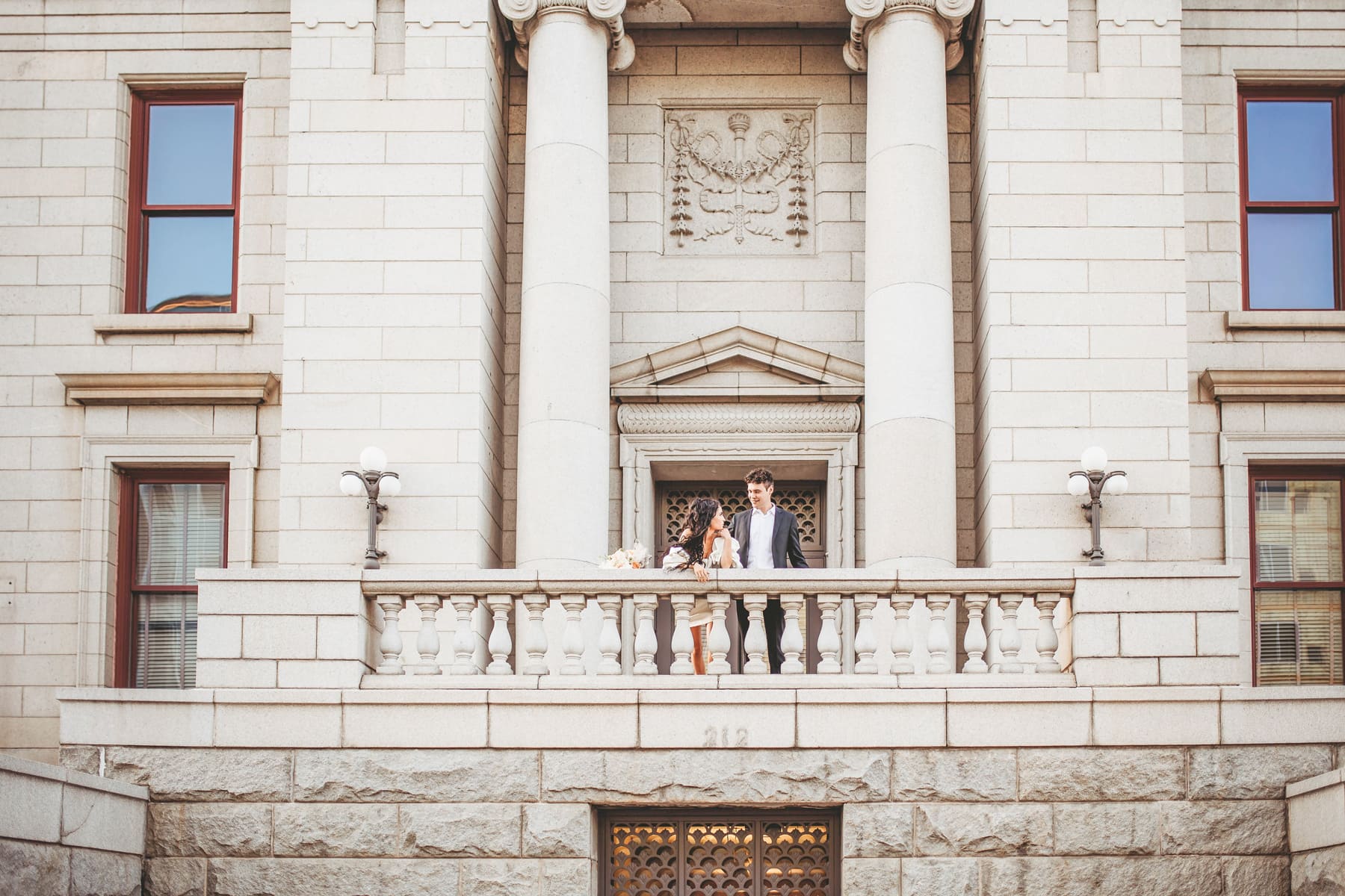 Wedding & Elopement Photographer, bride and groom lean over balcony in an old stone government building