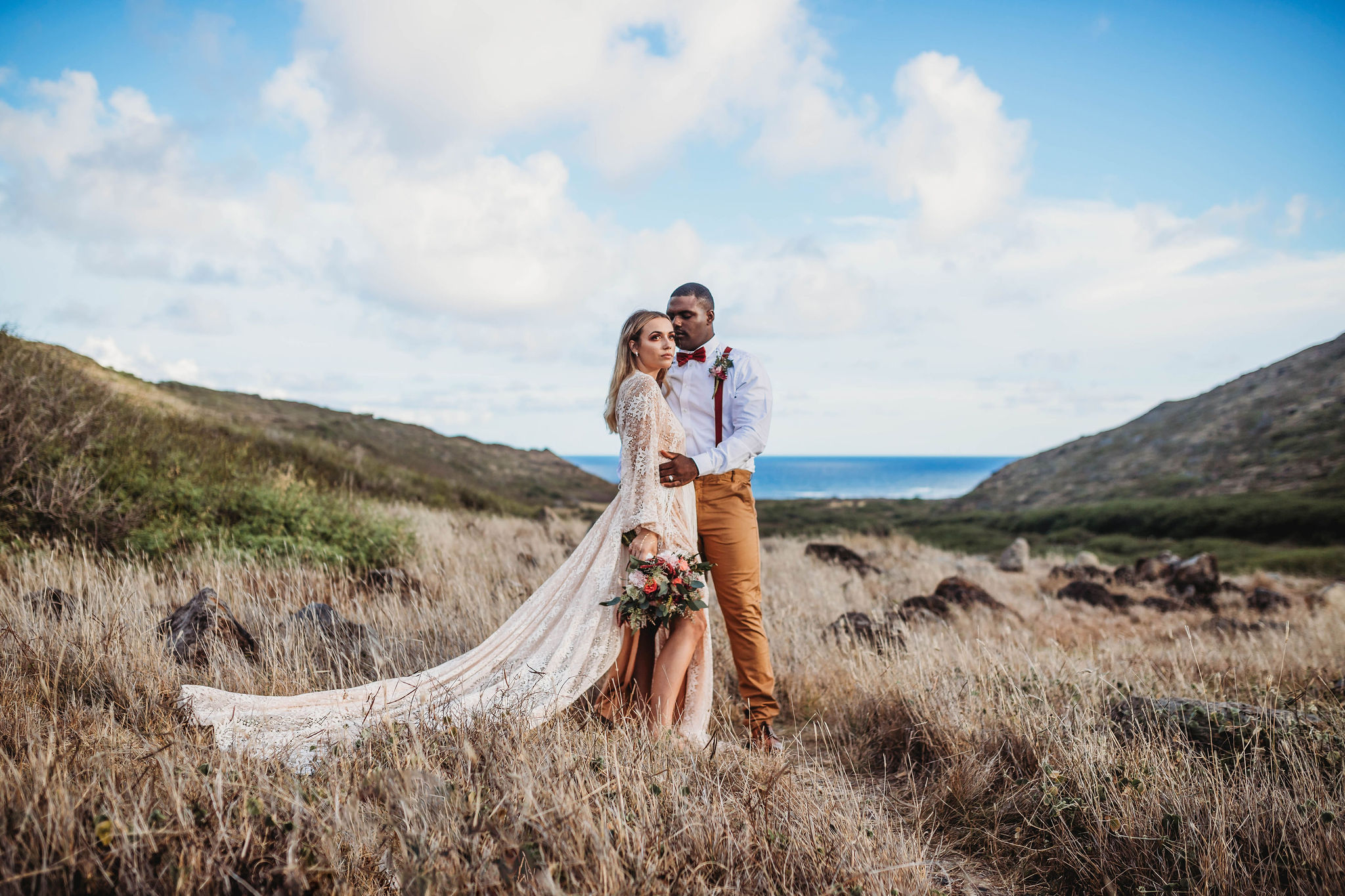Wedding & Elopement Photographer, groom embraces bride on a dry grassy meadow near ocean