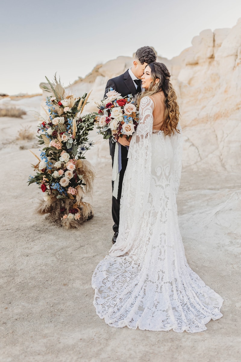 Wedding & Elopement Photographer, bride and groom stand together near floral arrangement in desert