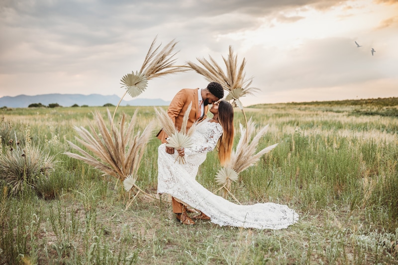Wedding & Elopement Photographer, groom holds bride behind arbor in a grassy field