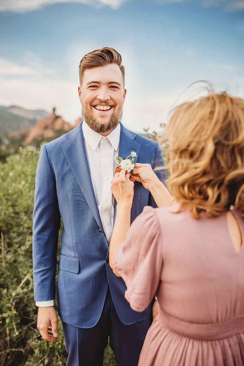 Wedding & Elopement Photographer, mother places corsage on groom in the outdoors