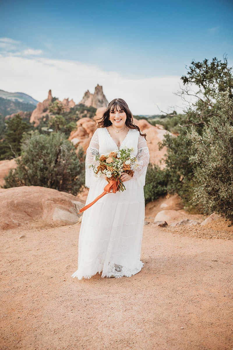 Wedding and Elopement Photography, bride stands outside in desert environment holding bouquet
