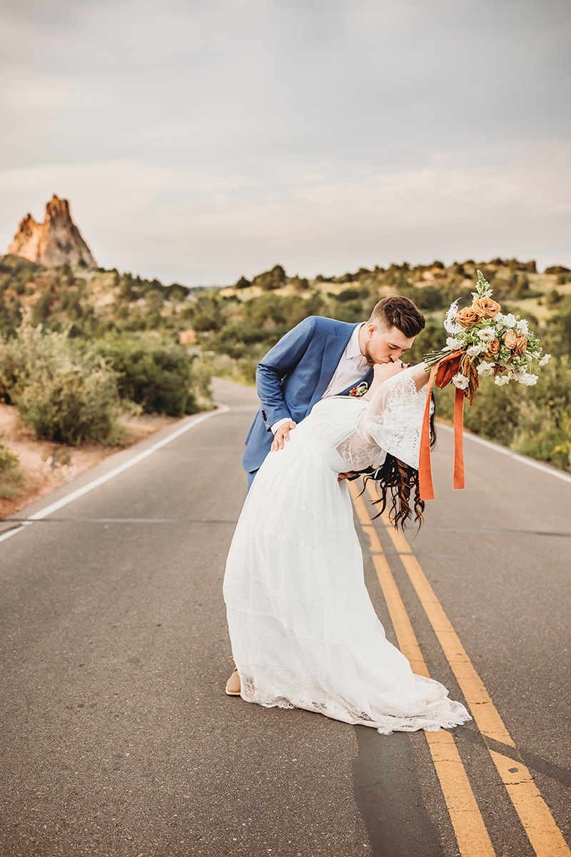 Wedding & Elopement Photographer, groom dips bride on a desert road for a kiss