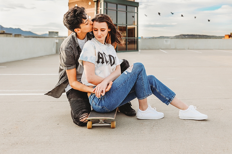 Wedding & Elopement Photographer, a couple kiss while sitting a skateboard on a rooftop parking lot
