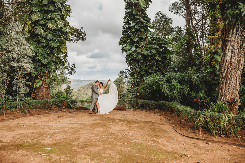 Wedding and Photographer, bride and groom tenderly draw close, bride lifts her dress in the air, they are in a forest