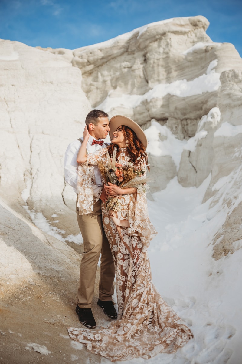 Wedding and Elopement Photography, man and woman stand together neat snowy rocks