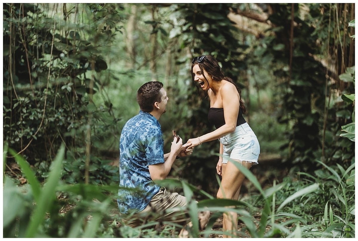 boyfriend on one knee proposing and girlfriend is surprised, surprise proposal in Oahu