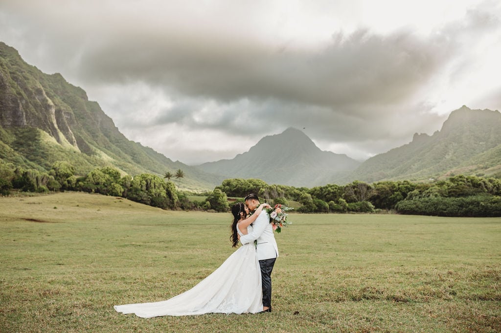 Top 5 Wedding Venues in Oahu, Groom kissing bride in the mountains