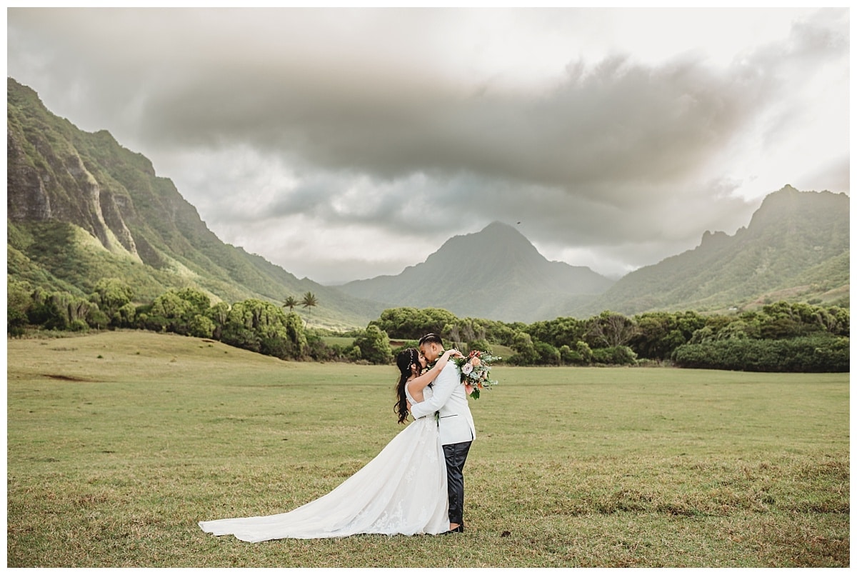 Top 5 Wedding Venues in Oahu, Groom kissing bride in the mountains, bride and groom kissing in Jumangi