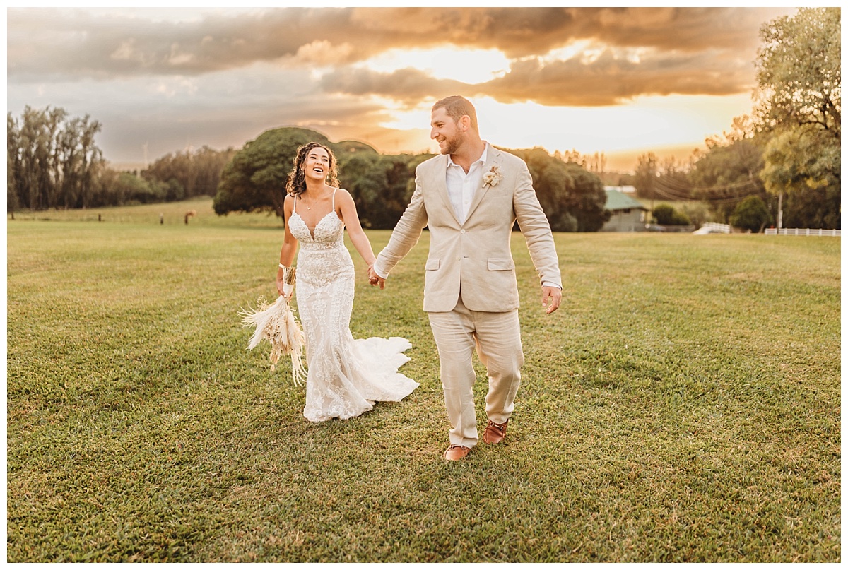 bride holding wedding bouquet while walking with groom, bride and groom walking holding hands, bride and groom walking during sunset, bride and groom holding hands, bride laughing while walking with groom