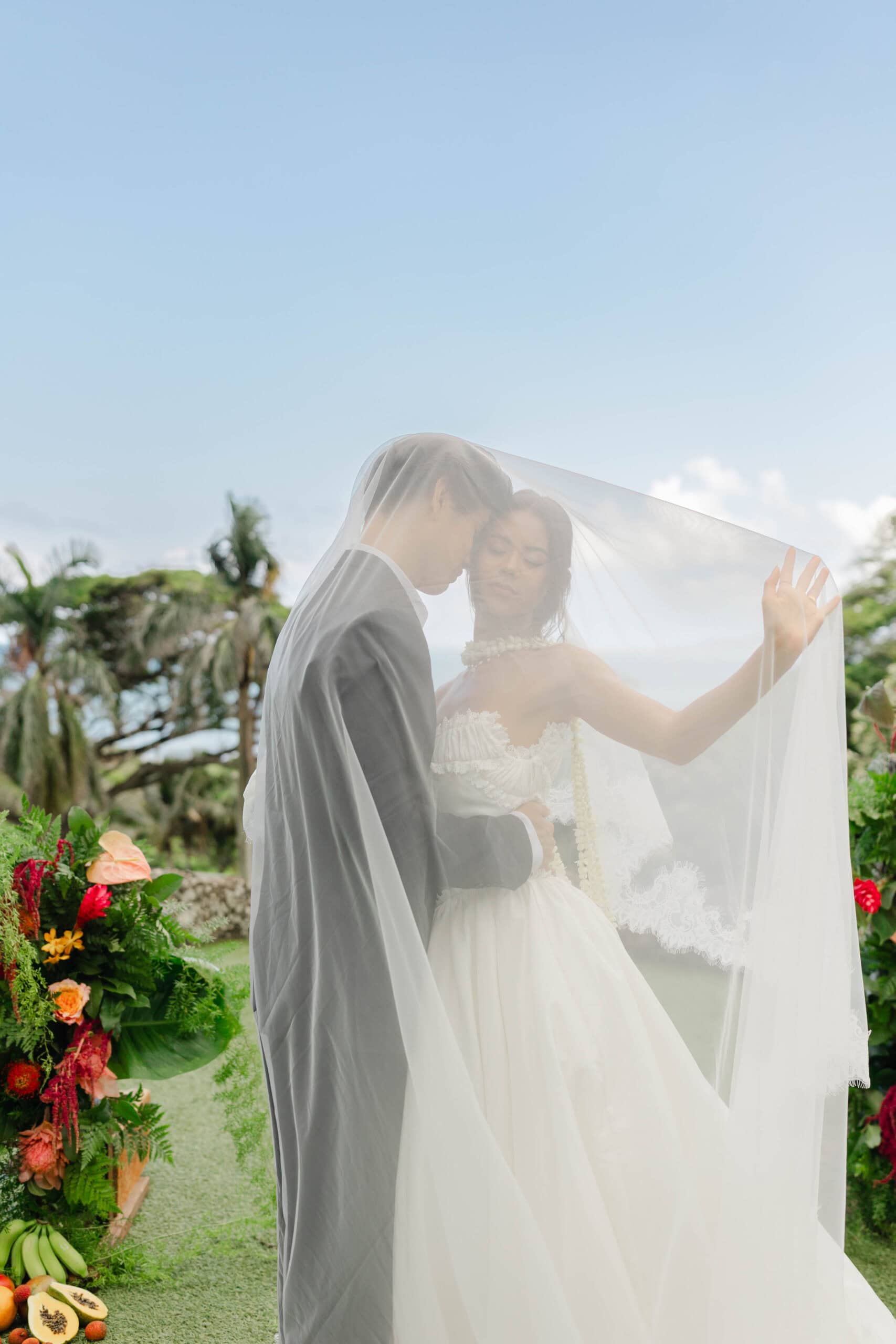 A bride and groom taking wedding photos underneath a veil